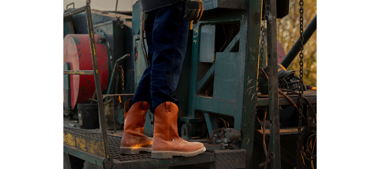 Un ángulo de primer plano de las botas de trabajo Lafayette para hombre en color marrón claro que usa un modelo en una plataforma de perforación.